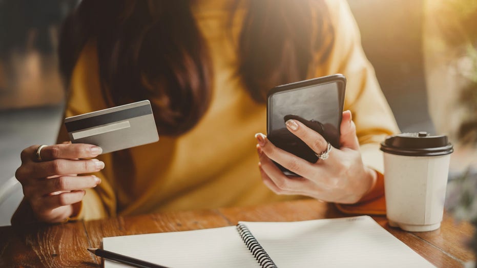 Woman holds up phone and credit card